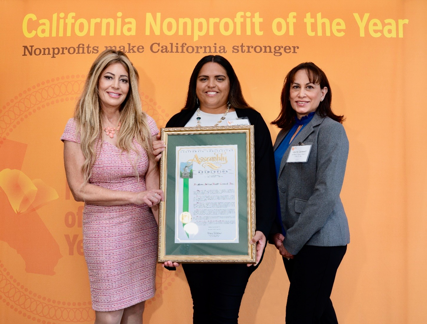 Three women hold a proclamation celebrating status at nonprofit of the year